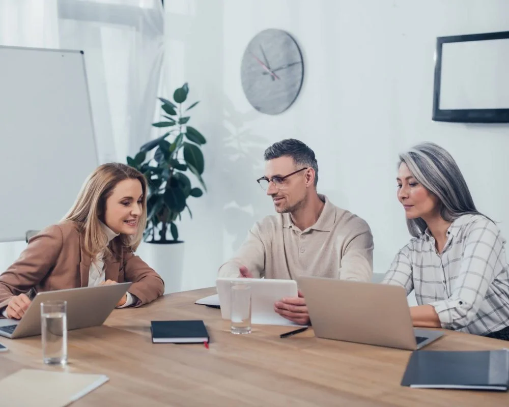 Staffing agency in Garden Grove – colleagues talking and using laptops at work